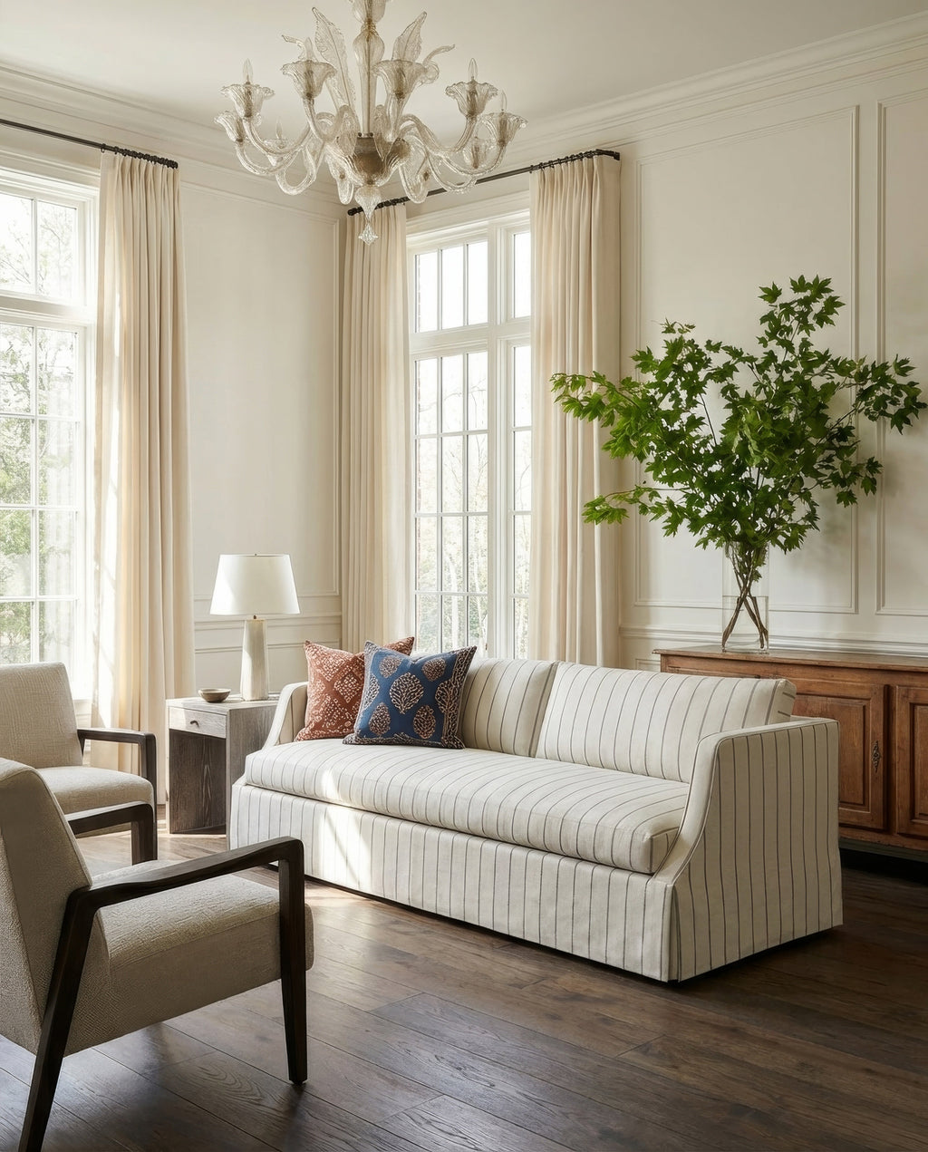 Living room with a striped sofa, armchair, and chandelier.
